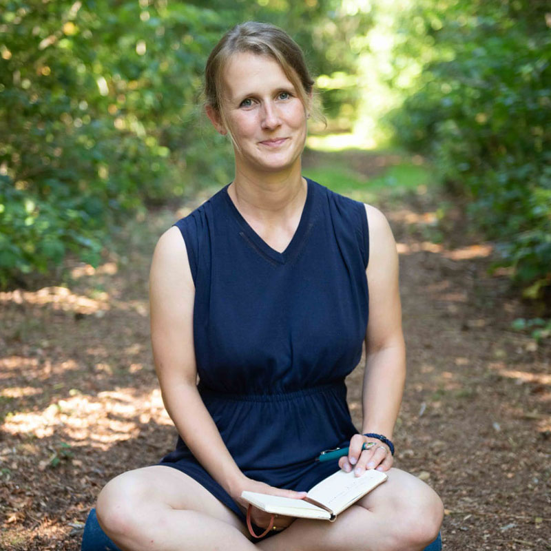 Tanja Lemke von Prana – Schönes für die Sinne in Flensburg, sitzend im Grünen mit Notizbuch